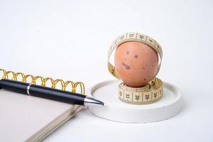 pollo huevo y medición cinta y bolígrafo en blanco antecedentes. dieta concepto foto