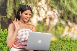 Tran woman waving at the computer while doing video call photo