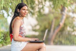 Transgender woman smiling at the camera while working in remote photo