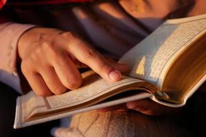 Muslim women's hand reading quran at night photo