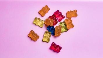 Colorful gummy bear candies on pink background. Top view. photo