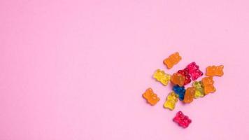 Colorful gummy bear candies on pink background. Top view. photo