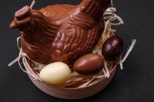 Chocolate Easter hen and eggs in a nest with straw photo