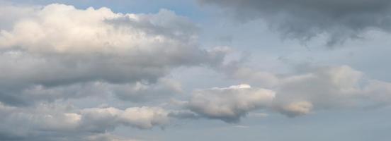 Panoramic view over soft blue sky with illuminated by sun rainy clouds as a background banner. photo