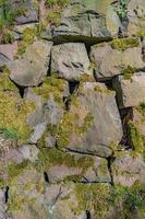 Pattern of ancient bricks and stones at old middle age fortress wall covered with moss, grass and lichen, as a background, closeup, details. photo