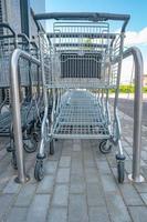 Empty stainless steel modern shopping carts standing at the supermarket in a row in line unused. photo