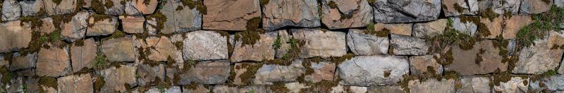 Panoramic view over a long middle age stone wall with patterns of ancient bricks and stones as a background, closeup, details. photo