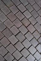 Pattern of ancient bricks and stones at old middle age pavement, as a background, closeup, details. photo