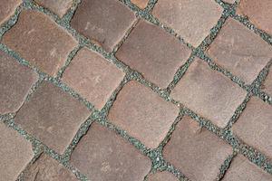 Pattern of ancient bricks and stones at old middle age pavement, as a background, closeup, details. photo