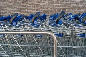 Empty stainless steel modern shopping carts standing at the supermarket in a row in line unused. photo
