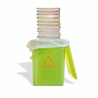 Green garbage trash bin with bag and a pile of paperback books with its shadow and recycling symbol on the bin isolated at white background. Concept of paper recycling. photo