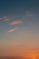 cubrir página con degradado suave profundo naranja cielo, iluminado nubes a sangriento puesta de sol como un antecedentes. foto