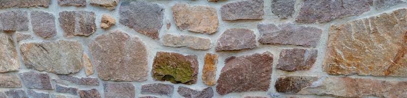 Panoramic view over a long middle age stone wall with patterns of ancient bricks and stones as a background, closeup, details. photo