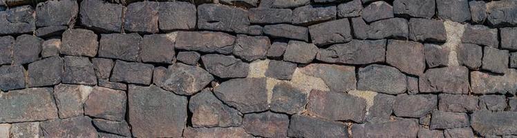 Panoramic view over a long middle age stone wall with patterns of ancient bricks and stones as a background, closeup, details. photo