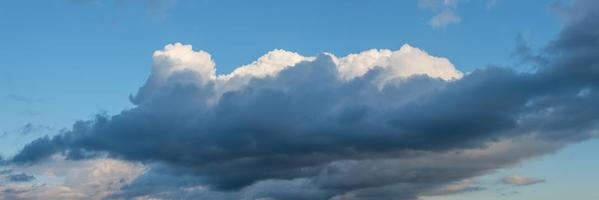 Banner with panoramic view over deep blue rainy sky with illuminated clouds as a background. photo