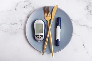 Plate with glucometer and cutlery on plate. Diabetes diet concept photo