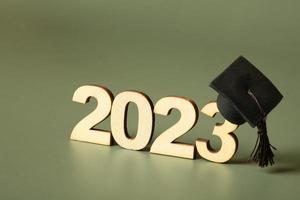 Class of 2023 concept. Wooden number 2023 with graduated cap on colored background photo