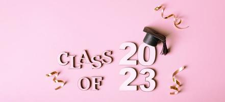 Class of 2023 concept. Wooden number 2023 with graduated cap on pink background photo