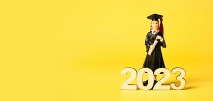 Class of 2023 concept. Wooden number 2023 with graduate statuette on color background photo