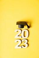 Class of 2023 concept. Wooden number 2023 with graduated cap on colored background photo