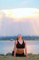 joven niña haciendo yoga aptitud ejercicio Mañana amanecer al aire libre en el prado hermosa montañas paisaje. meditación y relajarse. foto