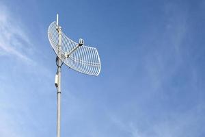 Internet wireless wifi receiver and repeater installed on metal pole on the roof of the building to service internet to users in local village, soft and selective focus. photo