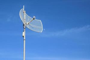 Internet wireless wifi receiver and repeater installed on metal pole on the roof of the building to service internet to users in local village, soft and selective focus. photo