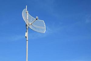 Internet wireless wifi receiver and repeater installed on metal pole on the roof of the building to service internet to users in local village, soft and selective focus. photo