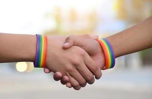 Closeup view of handshaking of LGBT people with blurred rainbow background, concept for success, cooperation, reconciliation, trust, and love for LGBT people and celebrations in pride month. photo