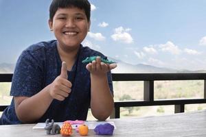 An autistic boy molding different shapes of colored plasticine prepared by parents at home in order to develop various aspects in their son which has slower brain development than normal children. photo