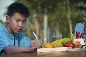 Asian boy holds paintbrush and coloring and painting outer surface with same color during his free times in the afternoon of the day, idea for hobby and art learning photo