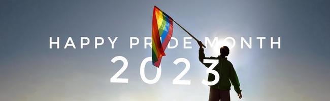 Happy pride 2023 on rainbow flag raising in hands and blue sky in the sunset background photo