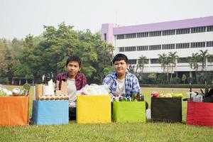 Asian boys are separating garbages and putting them into the boxes in front of them near building, soft and selective focus, environment care, community service and summer vacation activities concept. photo