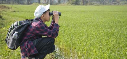 asiático Niños utilizando prismáticos a hacer el ornitología en tropical bosque durante verano acampar, idea para aprendizaje criaturas, fauna silvestre animales y insectos fuera de el aula. foto