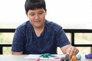 An autistic boy molding different shapes of colored plasticine prepared by parents at home in order to develop various aspects in their son which has slower brain development than normal children. photo