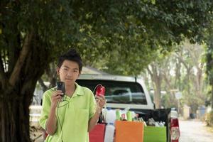 Asian boys are separating garbages and putting them into the boxes in front of them near building, soft and selective focus, environment care, community service and summer vacation activities concept. photo