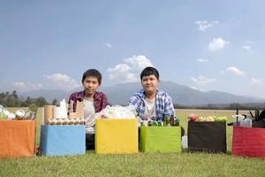 Young asian boy sorting various garbages and putting them into the boxes infront of him in the park, nature care and environment love concept. photo