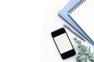 Modern white office desk table with smartphone, notebook and other supplies. photo