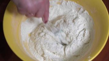 A woman's hand is kneading dough with a silicone spatula. video