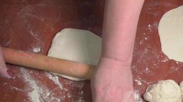 weiblich Hände sind rollen aus Teig zum Herstellung einfach ungesäuert Brot. video