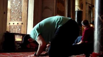 personas Orando en el mezquita desde diferente anglos, un joven hombre pone su frente en postración en el mezquita, santo boina video