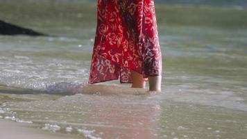 Mädchen auf das Ozean im ein lange rot Kleid. rot Kleid fliegt im das Wind. Ferien und Reise Konzept. video