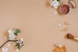 Cosmetic products, decorative cosmetics, perfume and flowers white top view on a beige background. Flat lay for a fashion blogger. Copy space photo