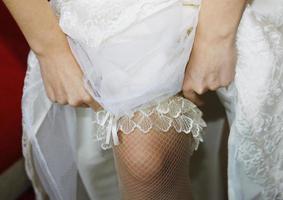 The bride wears a wedding garter on her leg photo