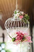 blanco jaula decorado con rosas flores colgando decoración en Boda foto