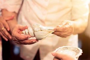 Old man hand hoding conch shell in tradition Thai wedding ceremony photo