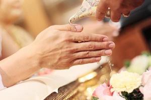 mano torrencial agua desde concha cáscara a bendecir el novio y el novia en tradicion tailandés Boda ceremonia foto