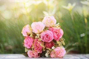 Pink Roses bouquet on concrete floor in the garden with sunlight and green natural background. Valentine Day for love and celebration Concept. photo