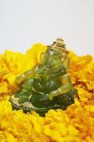 Emerald green Ganesha Statue god is the Lord of Success God of Hinduism on Marigold flowers Isolated on white background. photo
