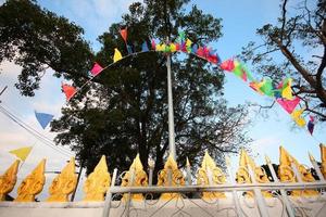 The temple wall in Thailand decorated with colorful flags. photo